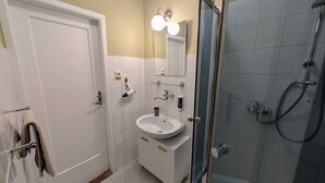 A bathroom with a white sink, a glass shower enclosure, and a towel rack.