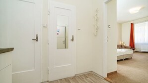 Un pasillo con puertas blancas, una cama y una ventana con cortinas.