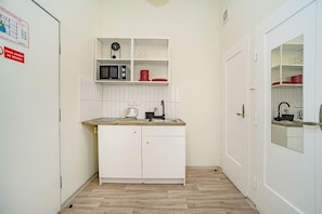 A compact kitchen with white cabinetry, a microwave, and a sink. - Modern, bright studio in a great location (Praha)