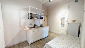 Une cuisine de taille réduite, équipée d’un four à micro-ondes, d’un évier et de meubles blancs.