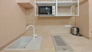A small kitchenette with a microwave, a kettle, and a sink.