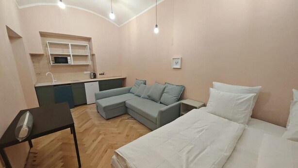 A compact living space with a kitchenette, a sofa, a bed, and a small table.