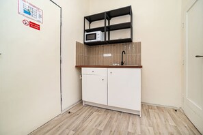 A compact kitchenette with a microwave, a sink, and a cabinet.