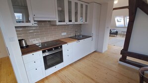 Une cuisine moderne avec des meubles blancs, un plan de travail en bois et un four encastré.