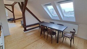 Une pièce dotée d’un plancher en bois, d’une table à manger avec des chaises et de lucarnes.