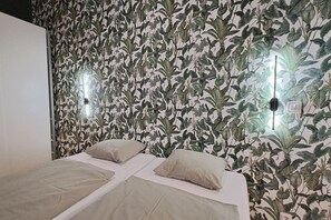 A room with a bed, two pillows, and a wall with a leafy pattern. - Chic+Contemporary Zizkov Studio (Praha 3)
