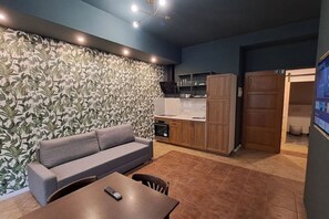 A modern living area with a sofa, a dining table, and a kitchenette. - Chic+Contemporary Zizkov Studio (Praha 3)