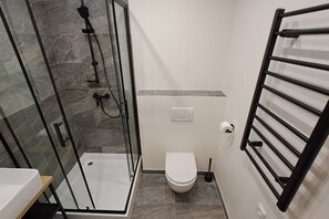 A bathroom with a glass-enclosed shower, a toilet, and a towel rack. - Chic+Contemporary Zizkov Studio (Praha 3)