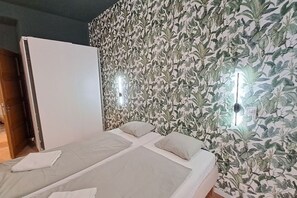 A room with a bed, a wardrobe, and a wall with a leafy pattern. - Chic+Contemporary Zizkov Studio (Praha 3)
