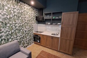 A compact kitchen with a built-in oven, a sink, and wooden cabinets. - Chic+Contemporary Zizkov Studio (Praha 3)
