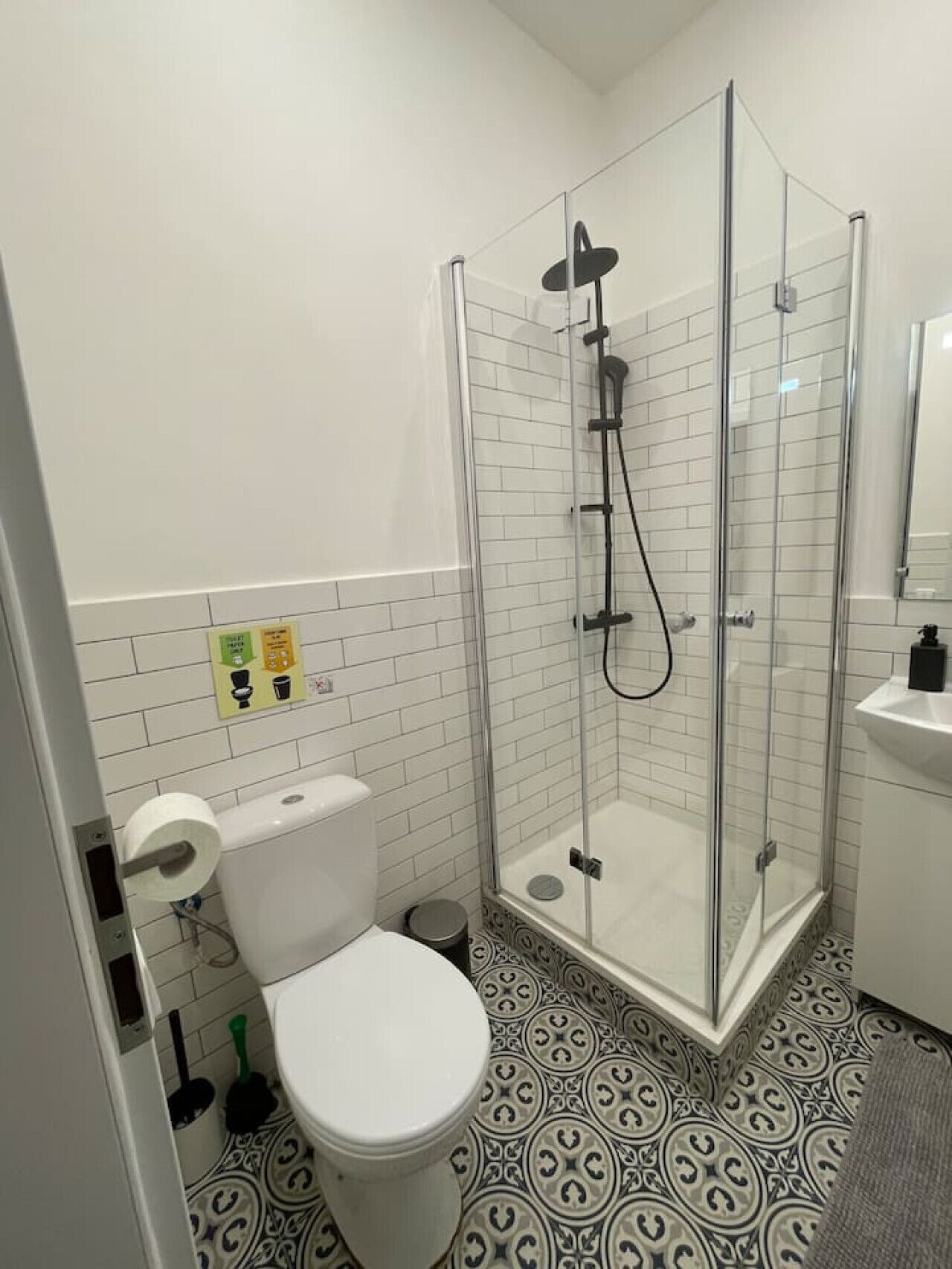 A bathroom with a toilet, a shower with a glass door, and a sink.
