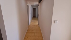 A narrow hallway with wooden flooring and white walls, leading to a door at the end. - Prague Urban Oasis Loft (Praha 2)