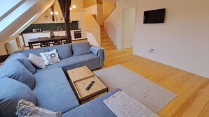 A modern living room with a sectional sofa, a wooden coffee table, and a TV mounted on the wall. - Prague Urban Oasis Loft (Praha 2)