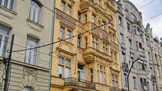 Un immeuble à plusieurs étages, doté d’une façade jaune, de grandes fenêtres et d’une entrée imposante.