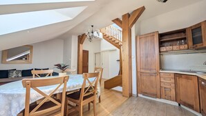 Une cuisine moderne avec des meubles en bois, un coin repas comprenant une table et des chaises, et un escalier menant à l’étage supérieur.
