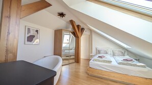 Une chambre avec un plafond en pente, un lit, un bureau et une chaise.