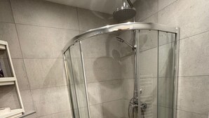 Une salle de bain moderne avec une douche à parois de verre, des toilettes et un porte-serviettes.