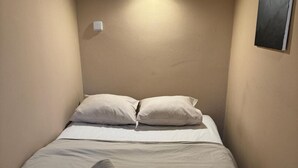 Un lit simple avec deux oreillers et une serviette pliée.