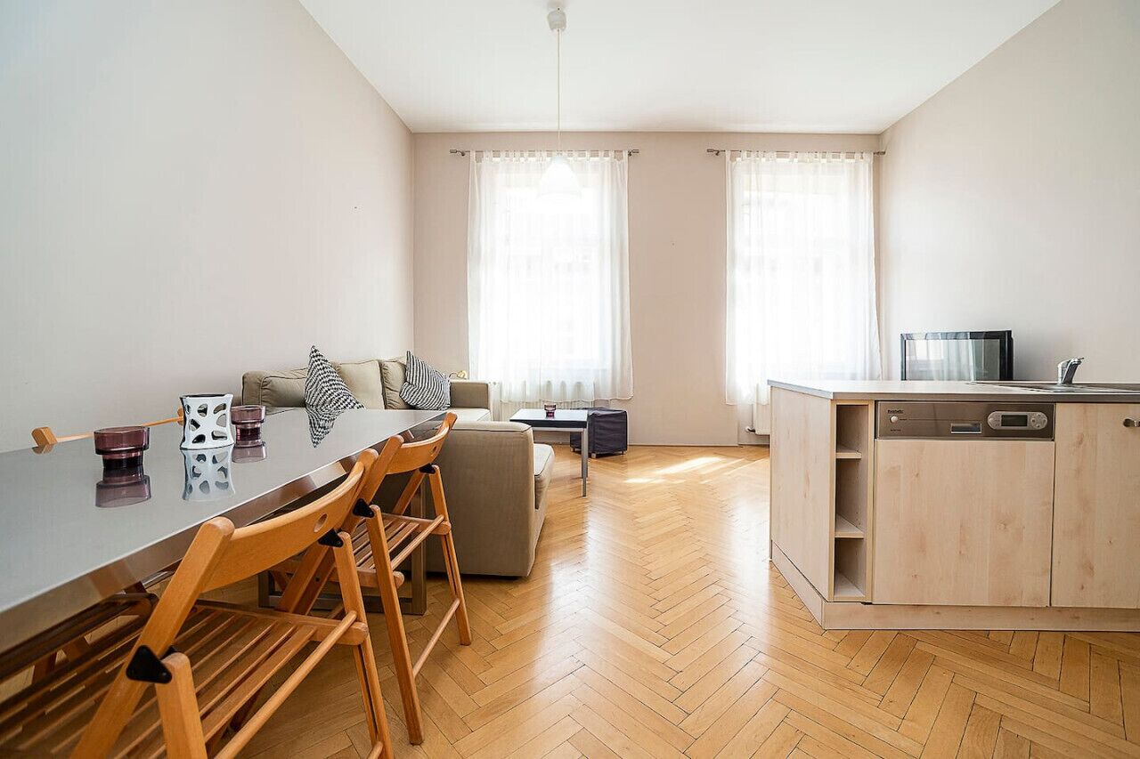 A modern kitchen with a dishwasher, a dining area with a table and chairs, and a sofa.