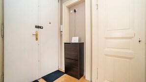 Un corridoio con una porta bianca a sinistra, un armadio di legno scuro al centro e una porta bianca a destra.