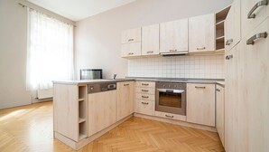 Una cucina moderna con mobili chiari in legno, un forno in acciaio inossidabile e una lavastoviglie.