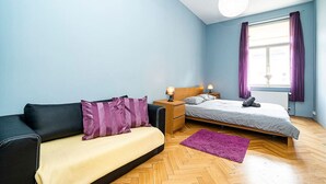 Una camera da letto con un letto, un divano, un comodino e una finestra con tende.