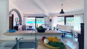 Ein geräumiges Wohnzimmer mit Küche, Essbereich und Meerblick.
