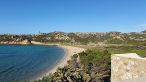 Eine Küstenlandschaft mit Strand, felsigen Klippen und einer Steinmauer.