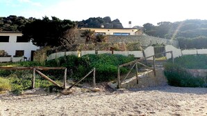 Ein Küstengebiet mit einer Steinmauer, einem Holzzaun und einem Gebäude mit einem Ziegeldach.