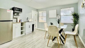 Una cocina moderna con refrigerador, microondas y pileta, además de un comedor con mesa y sillas.