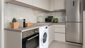 Une cuisine moderne équipée d’un réfrigérateur en acier inoxydable, d’un lave-linge encastré, d’un four à micro-ondes et d’un évier.