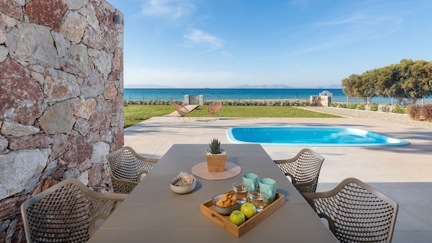 Une terrasse avec une piscine, un mur en pierre et du mobilier d’extérieur.