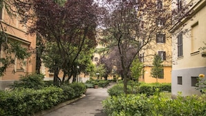 Une ruelle étroite bordée d’immeubles dotés de balcons et d’arbres.
