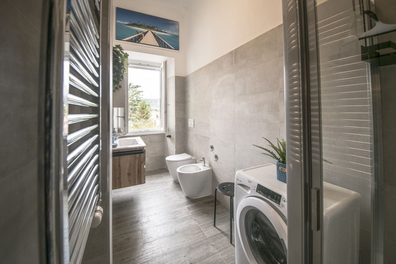 A modern bathroom with a shower, toilet, bidet, and washing machine.