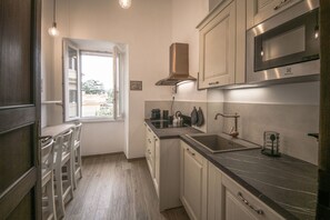 Una cocina con ventana, electrodomésticos de acero inoxidable y suelo de madera.