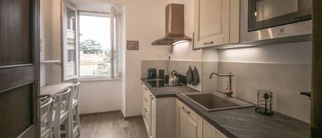 A kitchen with a window, stainless steel appliances, and wooden flooring.