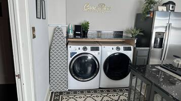 A compact laundry area with two front-loading washing machines, a coffee maker, and a water dispenser.