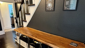 A bar area with a wooden counter and metal stools. - Cane River Living Downtown I Historic District (Natchitoches)