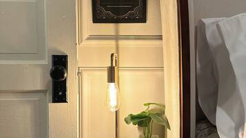 Un comodino con una lampada, un cartello incorniciato e una pianta in vaso.