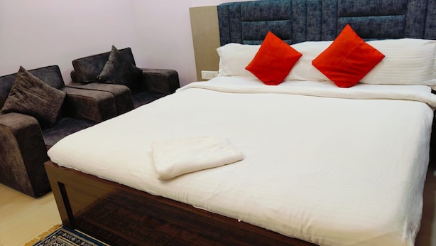 A hotel room with a bed, a sofa, and a small table. - Hotel Jyoti (Siliguri)
