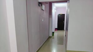 A narrow hallway with light-colored walls and a tiled floor. - Hotel Jyoti (Siliguri)