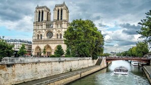 Una cattedrale storica con due torri gemelle, un fiume e un ponte.