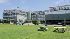 A multi-story building with a parking area and picnic tables in the foreground. - FFR314 - Just Wright by First Flight Rentals (Kill Devil Hills)