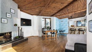A spacious living area with a wooden ceiling, a fireplace, a dining table with chairs, a sofa, and a kitchen area with bar stools. - ★ The Charm of the Center: Double Beauty ★ (Kraków)