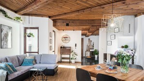 A modern living room with a wooden ceiling, a grey sofa, a dining table with chairs, and a kitchen area in the background. - ★ The Charm of the Center: Double Beauty ★ (Kraków)