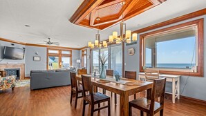 A spacious living area with a wooden dining table, comfortable seating, a television, and a fireplace. - WV24 Kiteboarding Paradise by First Flight Rentals (Rodanthe)