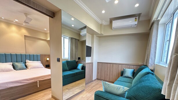 Una habitación de hotel moderna con una cama, dos sofás, un televisor y un aire acondicionado.