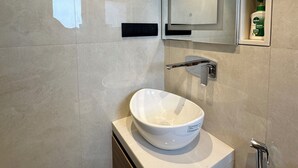 Un baño moderno con lavamanos blanco, un espejo y una ducha.