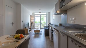 A modern kitchen with a dining area, a view to the outside, and a built-in oven. - Cap Océan by Interhome (Capbreton)