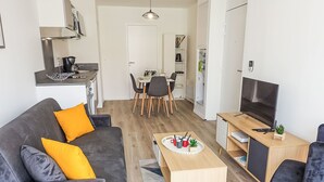 A modern living room with a grey sofa, a coffee table, and a TV on a wooden desk. - Cap Océan by Interhome (Capbreton)